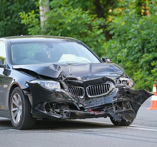 Aftermath of a car accident showing a black car with the front smashed